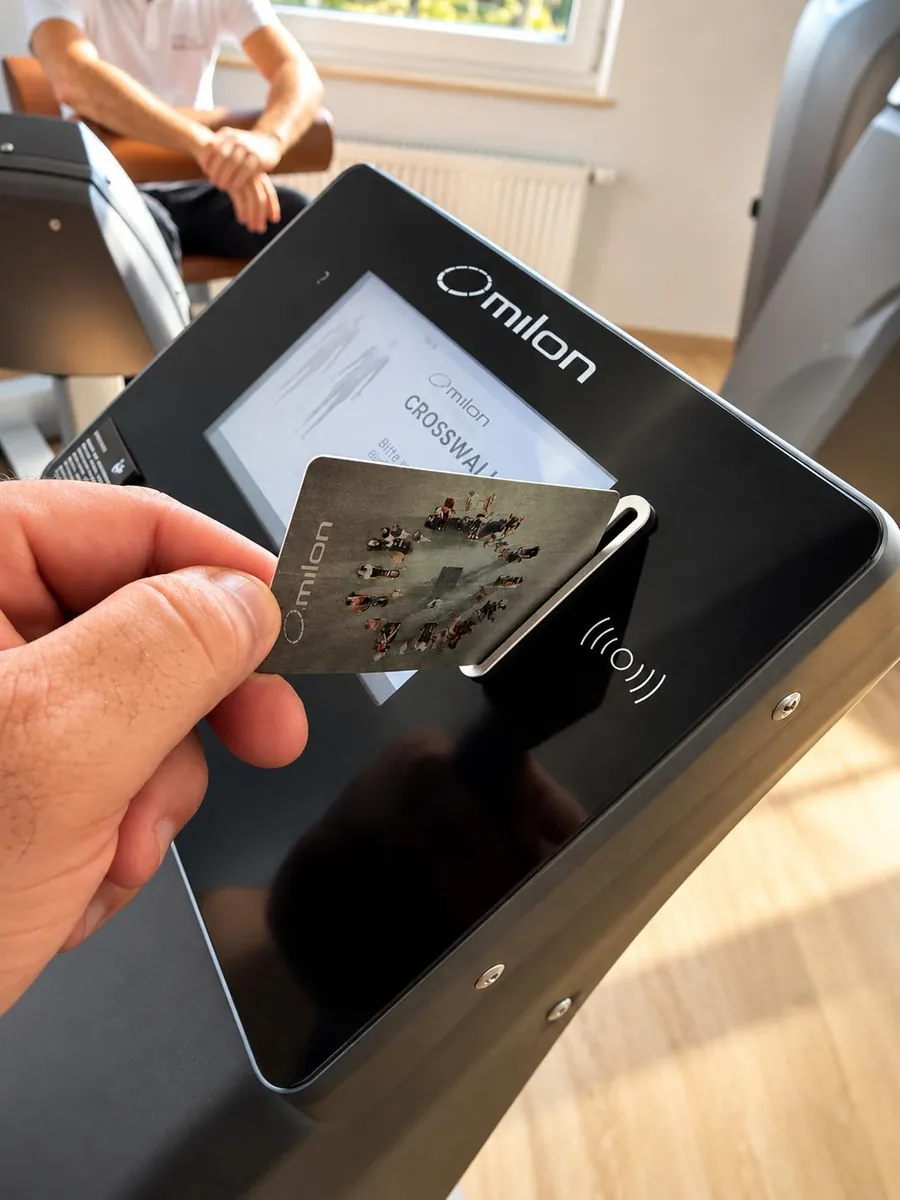 Eine Hand steckt die milon-Chipkarte in das Display eines Trainingsgeräts
